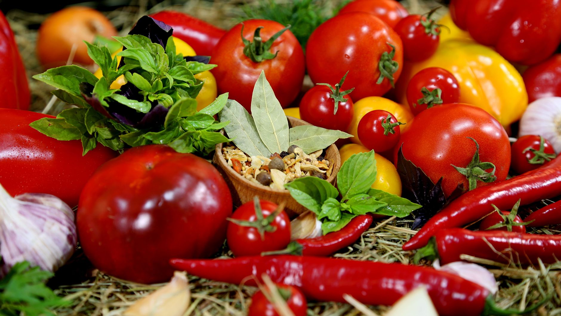 Colorful assortment of fresh peppers and tomatoes with herbs and spices.