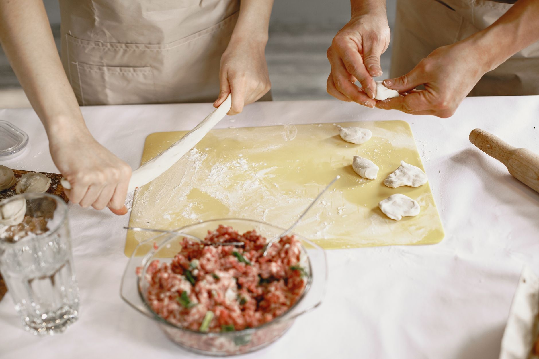Close-up of hands making homemade dumplings with dough and ingredients