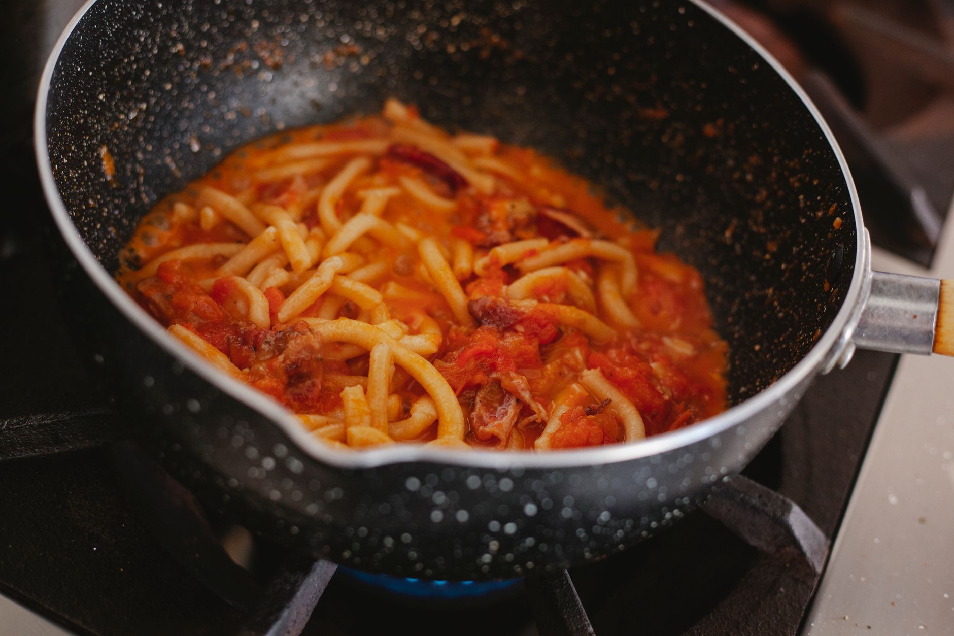 A savory pasta dish with rich tomato sauce cooked on a stove in a pot.