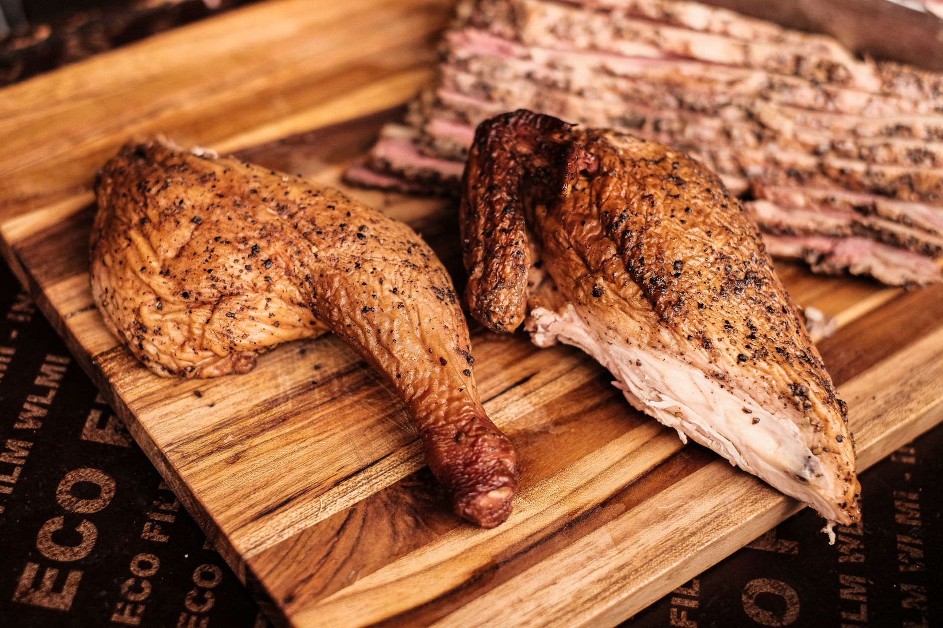 Mouthwatering smoked chicken and beef slices on a rustic wooden board, perfect for a barbecue feast.