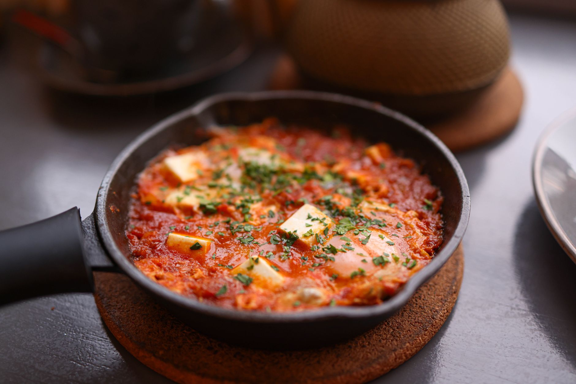 Appetizing shakshuka in a skillet, topped with cheese and fresh herbs, perfect for a hearty breakfast.