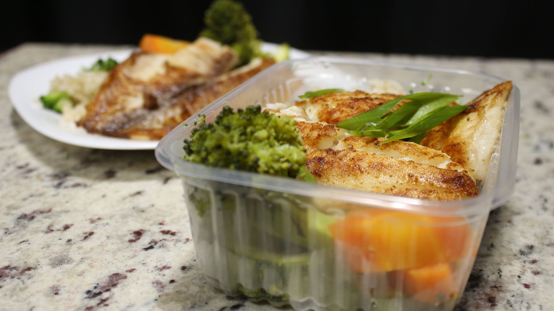 Delicious grilled fish fillet served with vegetables in a plastic container.